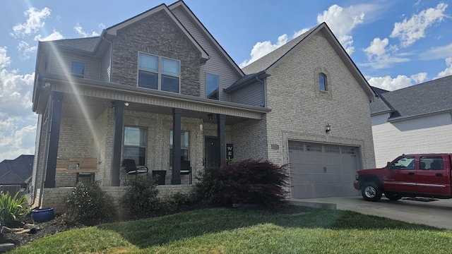 view of front of house featuring an attached garage, brick siding, a front yard, covered porch, and driveway