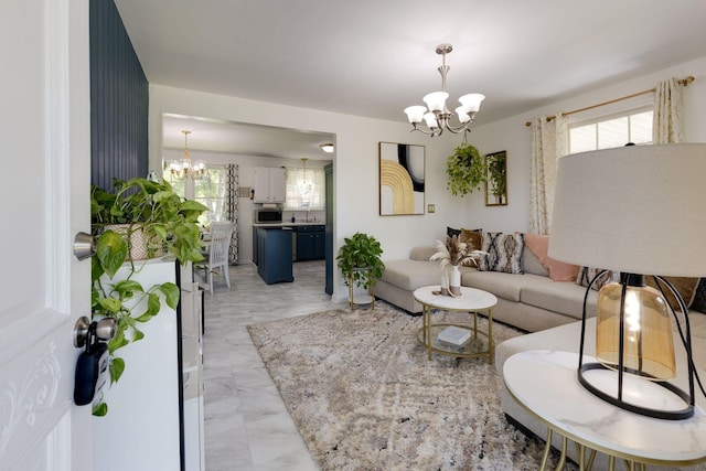 living area with an inviting chandelier, a wealth of natural light, and marble finish floor