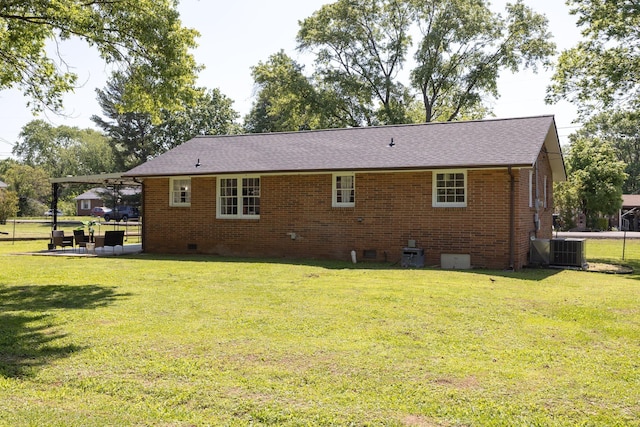 back of property featuring brick siding, crawl space, central AC unit, and a lawn