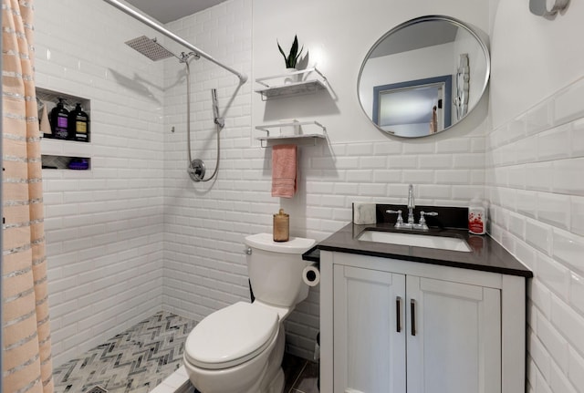 full bathroom with vanity, tile walls, toilet, and tiled shower