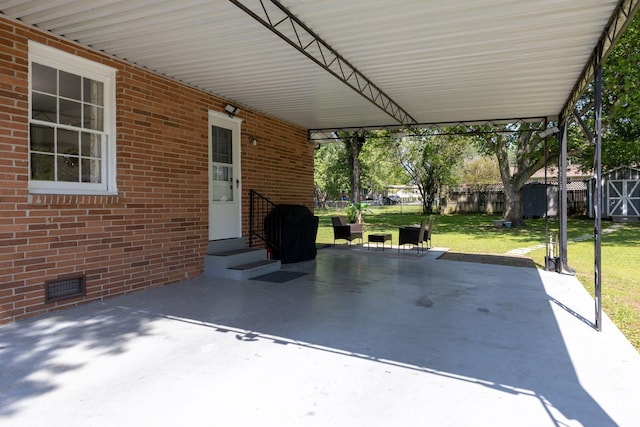 view of patio featuring visible vents, a storage shed, an outbuilding, fence, and an attached carport