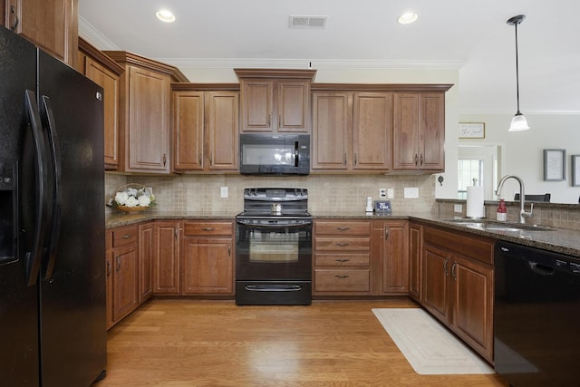 kitchen with crown molding, hanging light fixtures, a sink, visible vents, and black appliances