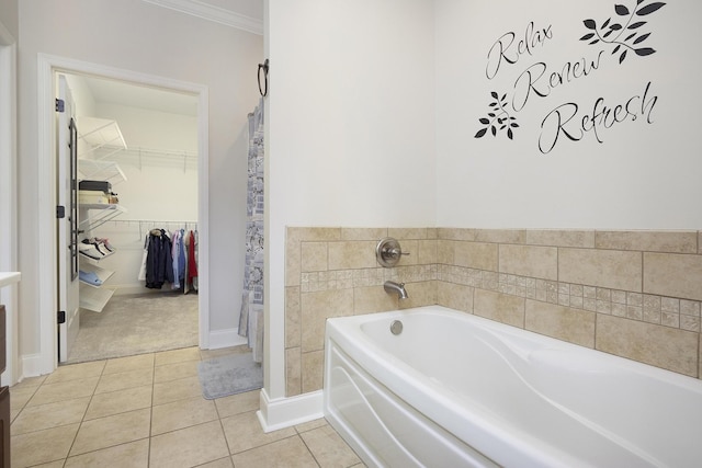 full bath with crown molding, tile patterned floors, a spacious closet, and a garden tub
