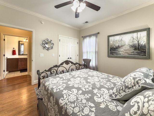 bedroom with visible vents, crown molding, a closet, wood finished floors, and baseboards