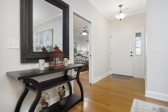 foyer with crown molding, a ceiling fan, baseboards, and wood finished floors