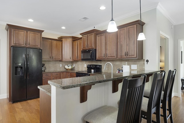 kitchen featuring light wood finished floors, black appliances, a peninsula, and visible vents