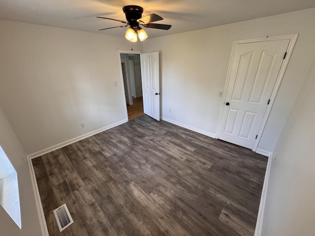 unfurnished bedroom with baseboards, ceiling fan, dark wood-type flooring, and visible vents