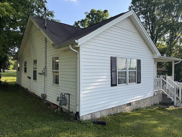 view of side of property with roof with shingles, a yard, and crawl space