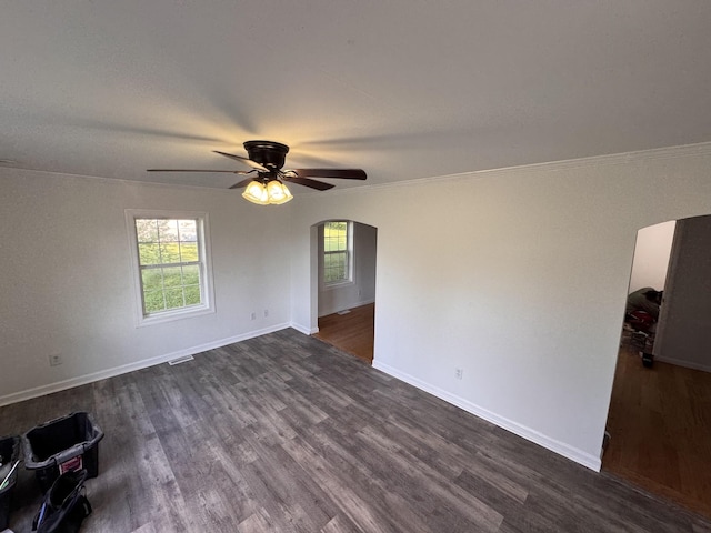spare room featuring dark wood-type flooring, arched walkways, ceiling fan, and visible vents