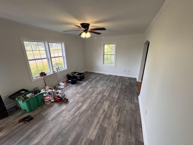 unfurnished room with ornamental molding, baseboards, ceiling fan, dark wood-type flooring, and arched walkways