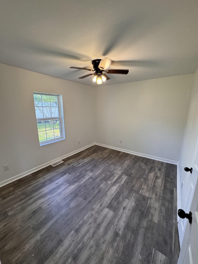 unfurnished room featuring dark wood-type flooring, a ceiling fan, baseboards, and visible vents