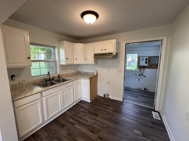kitchen featuring a sink, white cabinets, under cabinet range hood, and dark wood-type flooring
