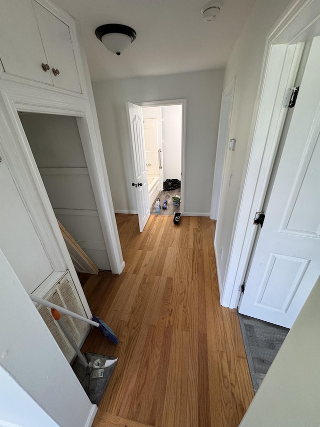 hall with baseboards, wood finished floors, and visible vents