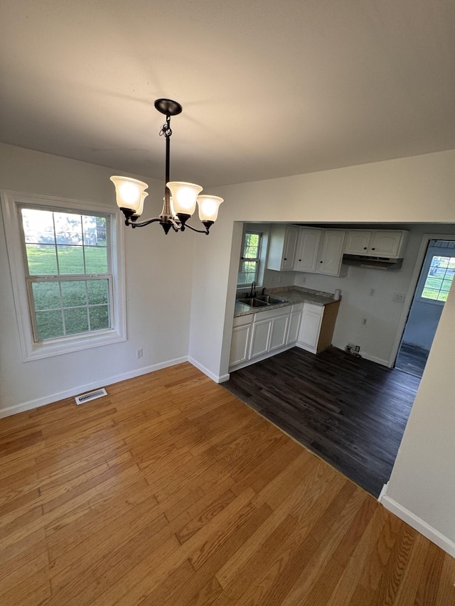 unfurnished dining area featuring visible vents, a sink, baseboards, and an inviting chandelier