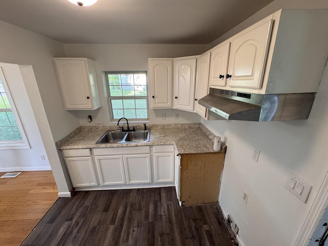 kitchen with dark wood-style flooring, baseboards, white cabinetry, and a sink