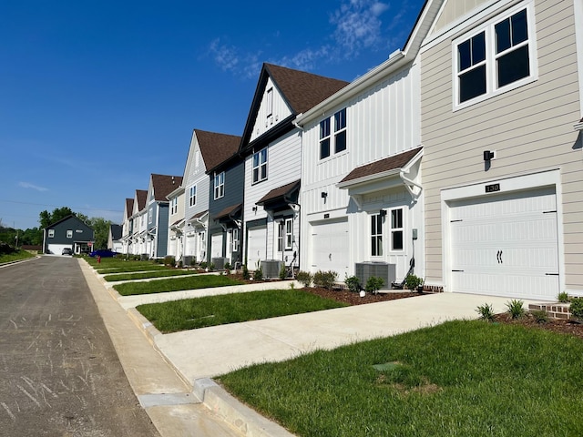 view of front of home featuring a residential view, an attached garage, board and batten siding, and cooling unit