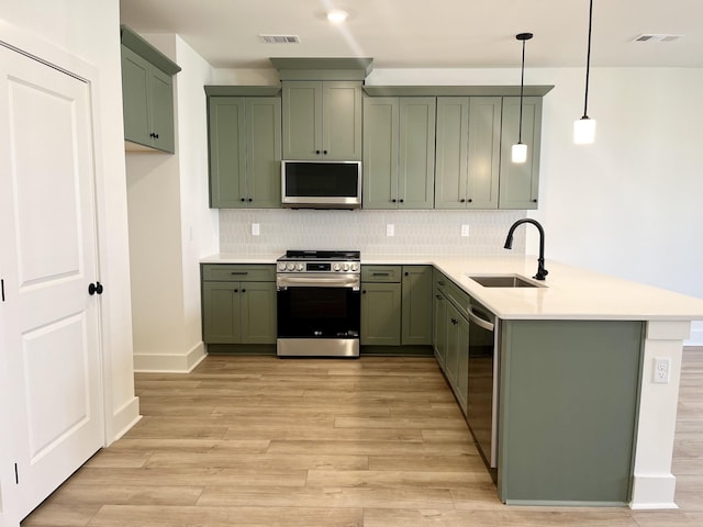kitchen with visible vents, appliances with stainless steel finishes, a sink, a peninsula, and green cabinetry