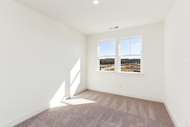 empty room with visible vents, baseboards, and light colored carpet