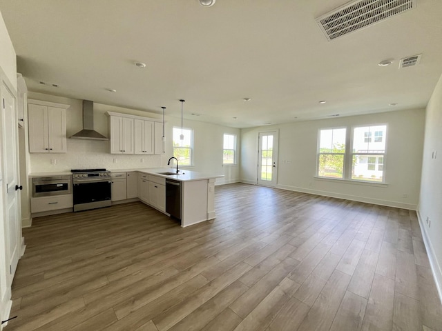 kitchen featuring visible vents, a sink, electric stove, open floor plan, and wall chimney exhaust hood