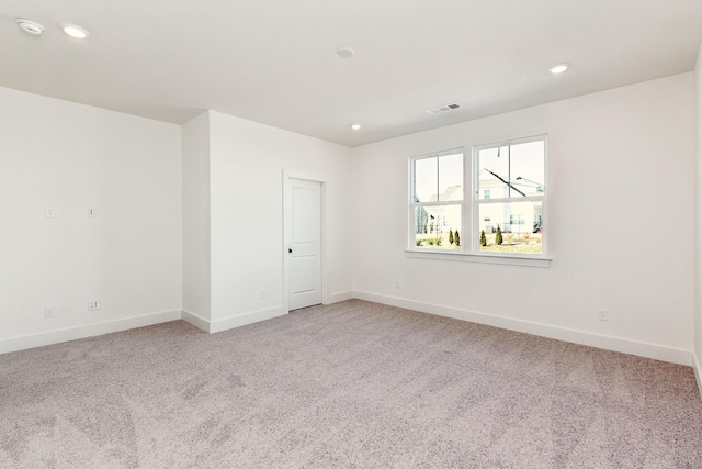 empty room with baseboards, recessed lighting, and light carpet
