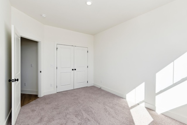 unfurnished bedroom with baseboards, carpet, and a closet
