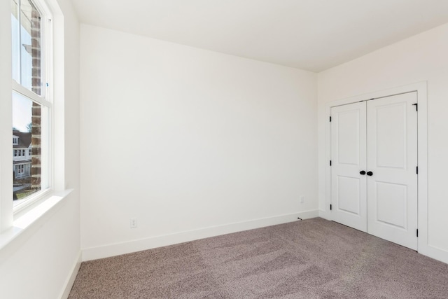 carpeted empty room featuring baseboards
