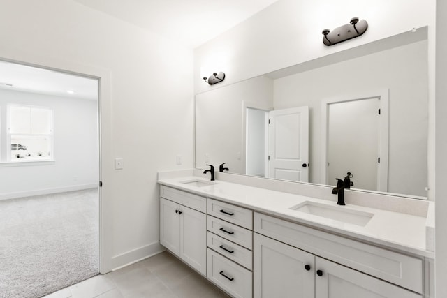 bathroom featuring double vanity, a sink, baseboards, and tile patterned flooring