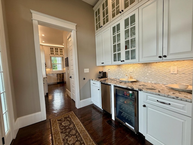 bar featuring decorative backsplash, beverage cooler, baseboards, dark wood-style floors, and a dry bar
