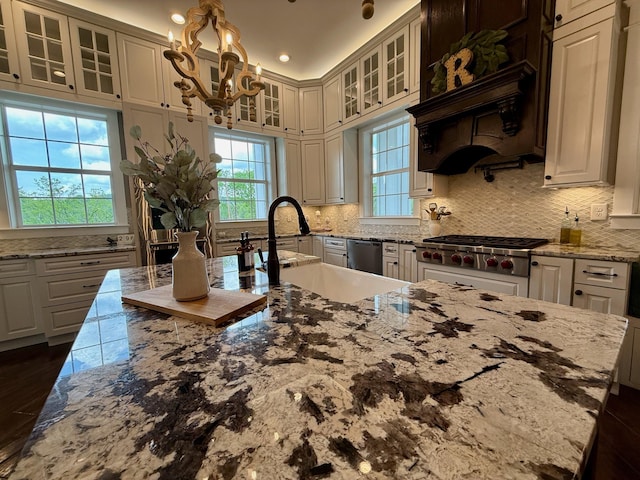 kitchen with an inviting chandelier, glass insert cabinets, tasteful backsplash, and stainless steel appliances