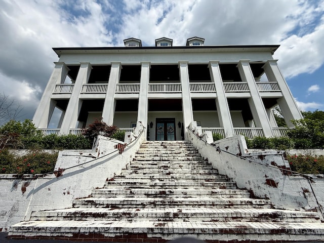 rear view of house featuring french doors, stairway, and a balcony