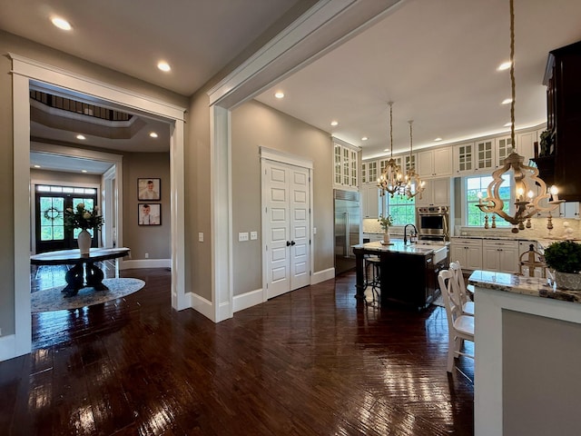 dining room with plenty of natural light, baseboards, dark wood-type flooring, and a notable chandelier
