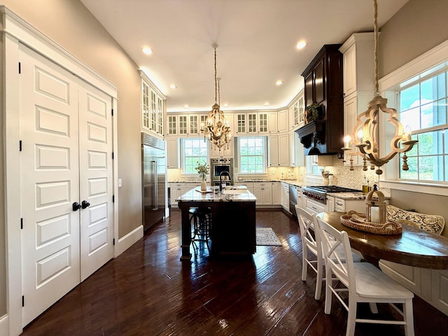 kitchen with stainless steel appliances, a chandelier, glass insert cabinets, and a wealth of natural light