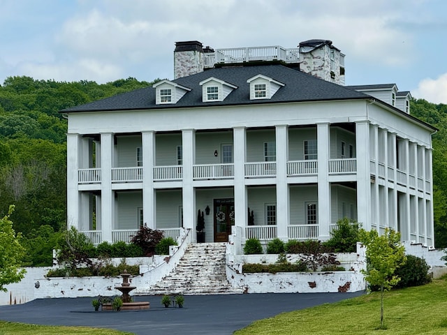 back of property with a porch, a chimney, and a balcony