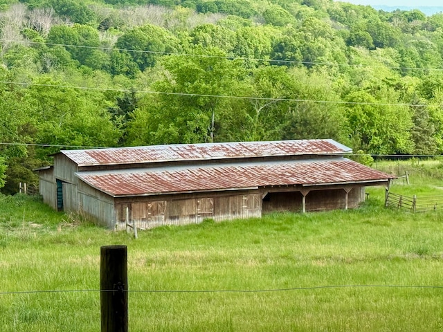 view of pole building featuring a view of trees and fence