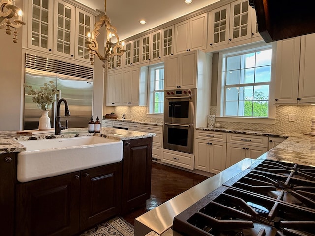 kitchen featuring a sink, decorative backsplash, a healthy amount of sunlight, and stainless steel appliances