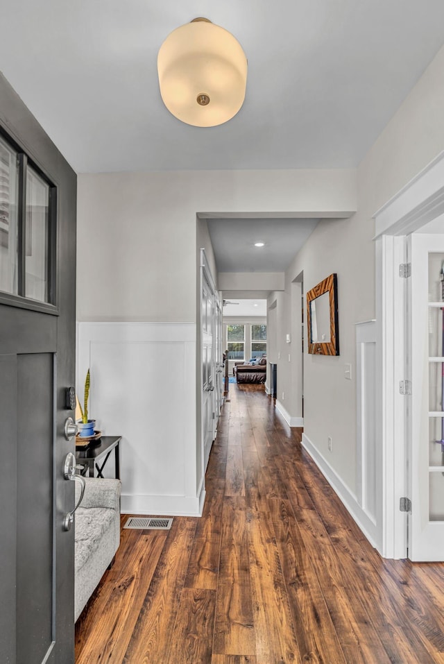 corridor with french doors, wainscoting, wood finished floors, and visible vents