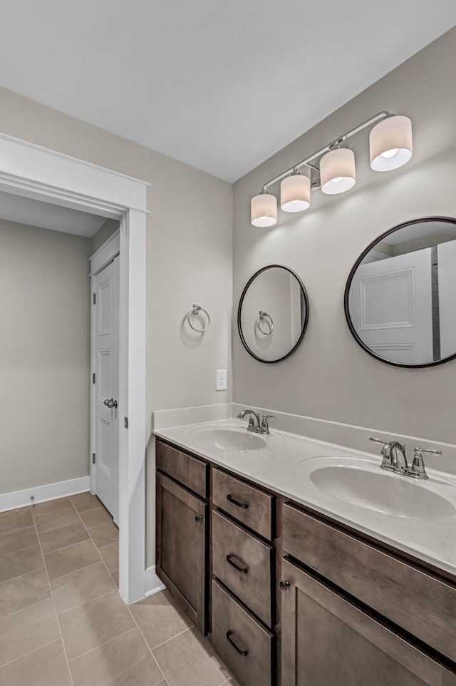 bathroom featuring double vanity, a sink, baseboards, and tile patterned floors