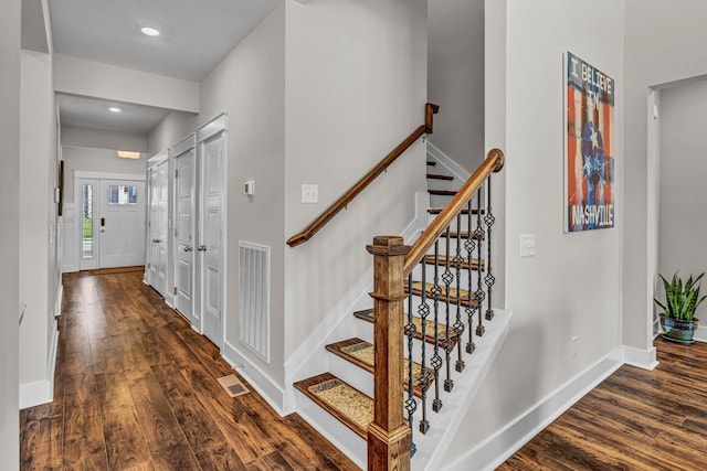 stairway featuring baseboards, wood finished floors, and visible vents