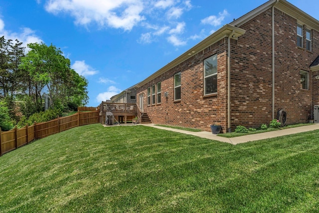 view of yard featuring a deck, fence, and stairs