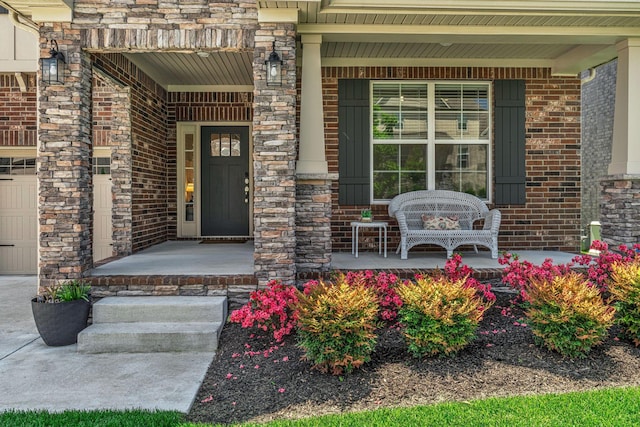 entrance to property featuring a porch, stone siding, and brick siding