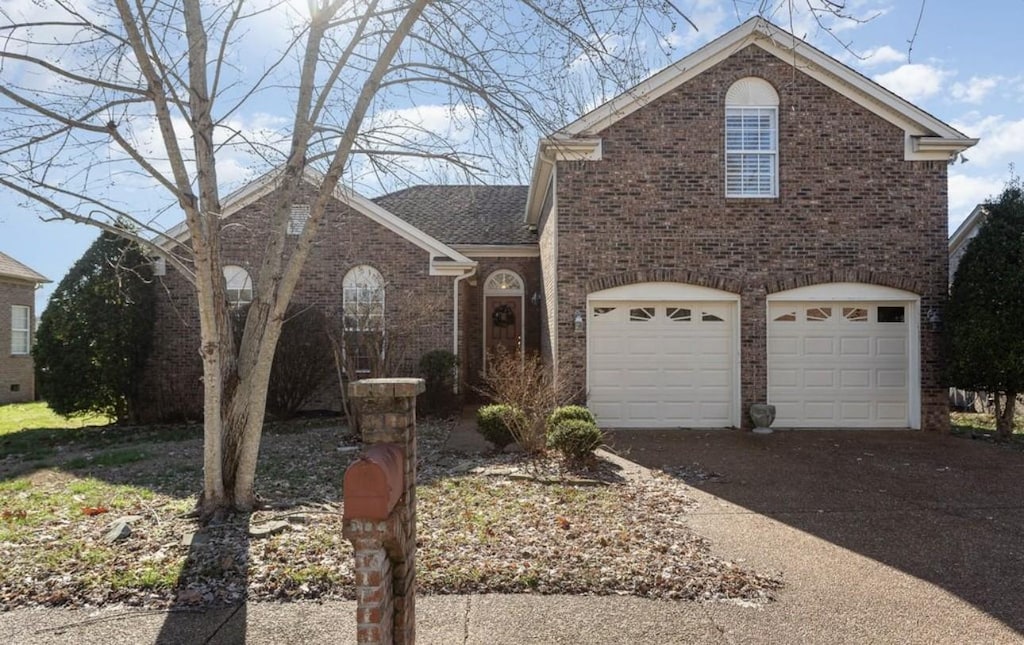 traditional home with a garage, driveway, and brick siding
