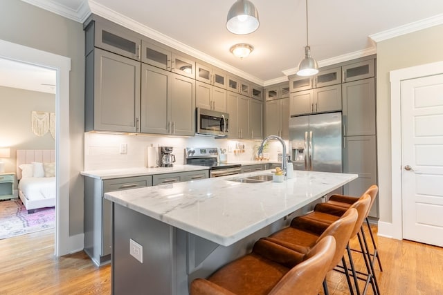 kitchen with a sink, appliances with stainless steel finishes, gray cabinets, and light wood-style flooring