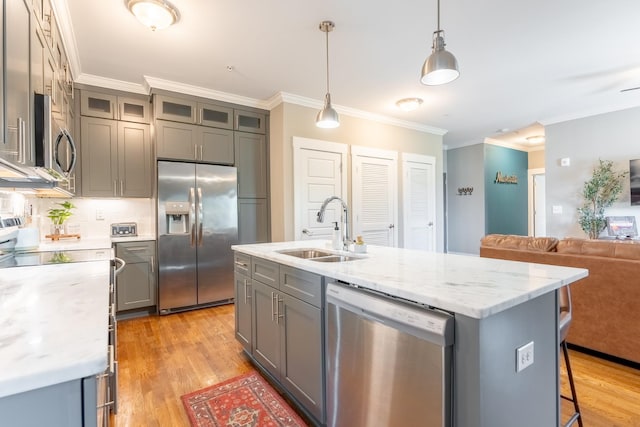 kitchen featuring crown molding, appliances with stainless steel finishes, a sink, gray cabinets, and light wood-type flooring