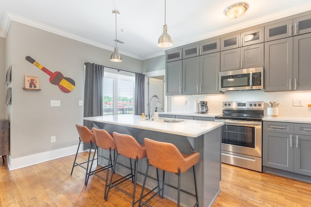 kitchen featuring crown molding, light countertops, gray cabinets, and stainless steel appliances