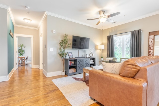 living area with crown molding, a ceiling fan, baseboards, and light wood-style flooring
