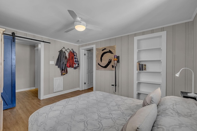 2075 Buttrey Rd, Bon Aqua, TN 37025 - bedroom with baseboards, ornamental molding, wood finished floors, and a barn door