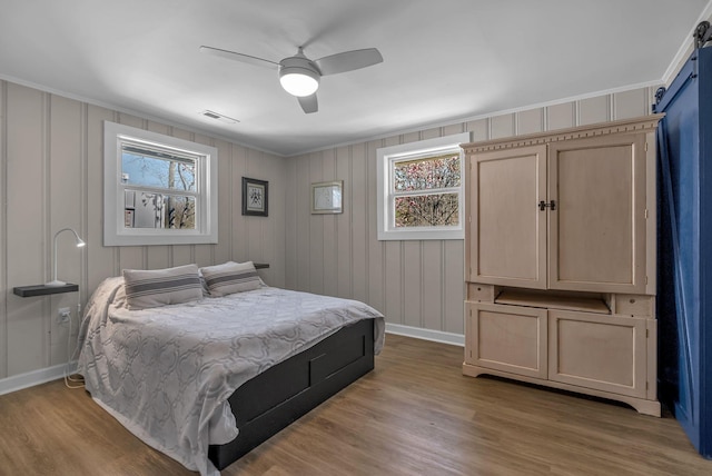 2075 Buttrey Rd, Bon Aqua, TN 37025 - bedroom with visible vents, ornamental molding, baseboards, a barn door, and light wood-style flooring