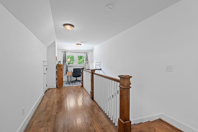 hallway featuring baseboards, an upstairs landing, and wood finished floors