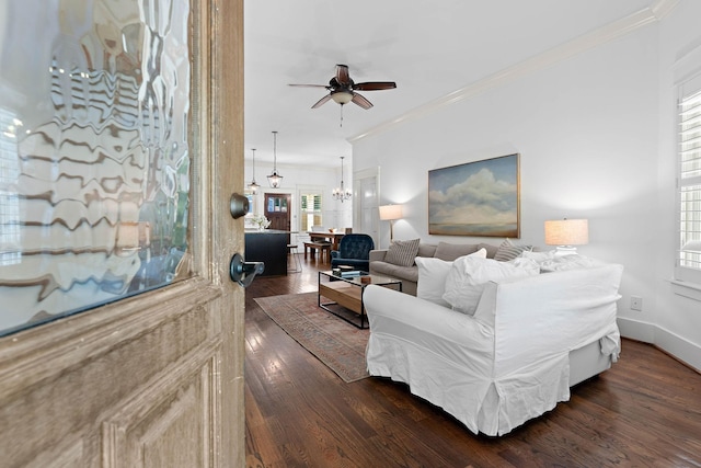 living area featuring crown molding, dark wood-style flooring, baseboards, and ceiling fan with notable chandelier