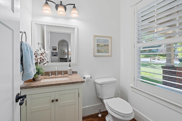 bathroom featuring baseboards, wood finished floors, toilet, and vanity